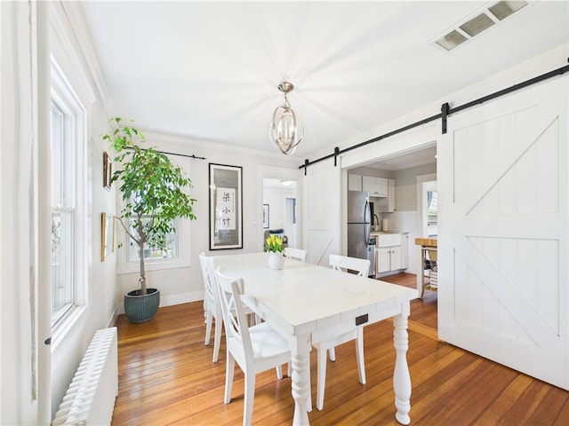 39 Union St, East Greenwich, RI 02818 - dining space with a barn door, radiator heating unit, light wood-type flooring, plenty of natural light, and ornamental molding