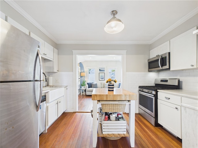 39 Union St, East Greenwich, RI 02818 - kitchen with stainless steel appliances, light wood-style floors, light countertops, white cabinets, and ornamental molding
