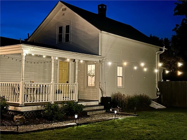 39 Union St, East Greenwich, RI 02818 - back of house at twilight featuring a porch, a yard, and a chimney