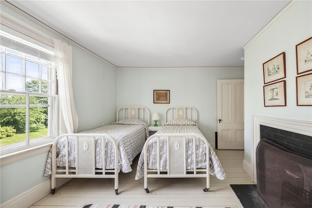 125 Sakonnet Point Rd, Little Compton, RI 02837 - bedroom featuring baseboards, ornamental molding, a fireplace with flush hearth, and wood finished floors