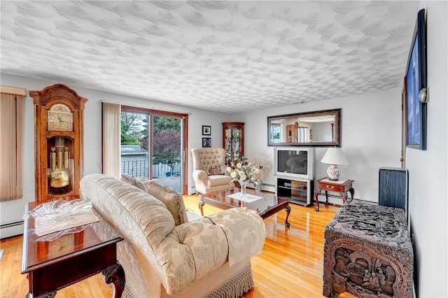 living area featuring light wood finished floors, a textured ceiling, and a baseboard radiator