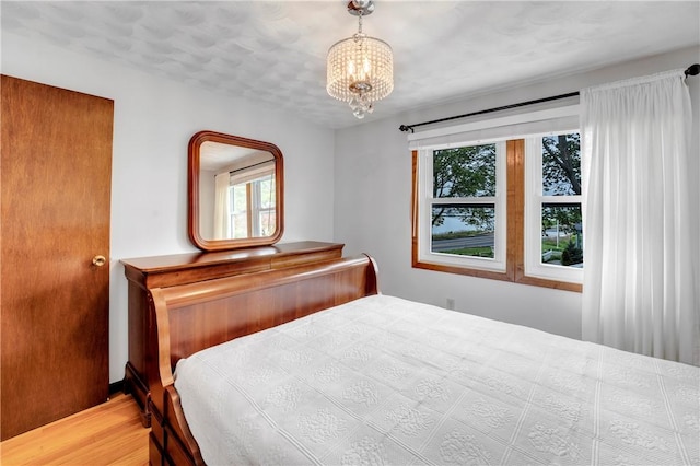 bedroom featuring a chandelier and wood finished floors