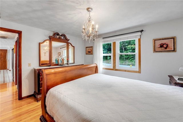bedroom featuring light wood-style floors, a chandelier, and baseboards
