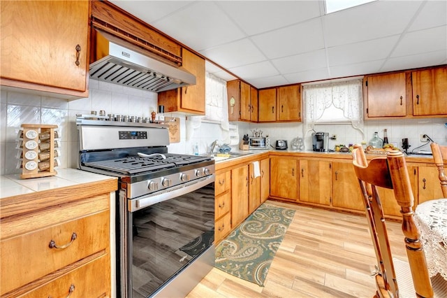 kitchen with gas stove, under cabinet range hood, healthy amount of natural light, and a sink