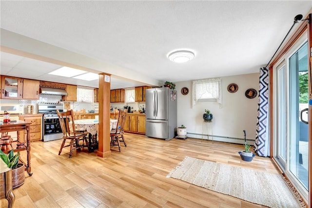 dining space with a baseboard radiator, light wood-style floors, and baseboards