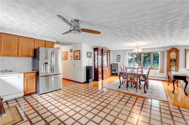 kitchen featuring stainless steel fridge with ice dispenser, white dishwasher, baseboard heating, light countertops, and a chandelier