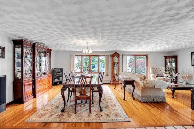 dining area with a chandelier, light wood-style flooring, a baseboard radiator, and baseboards
