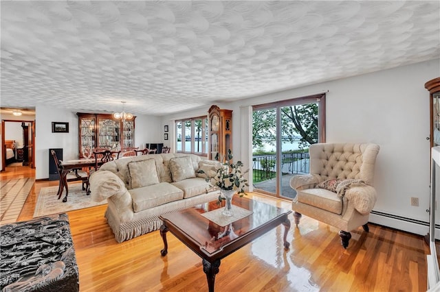 living room with wood finished floors, a baseboard heating unit, and a textured ceiling