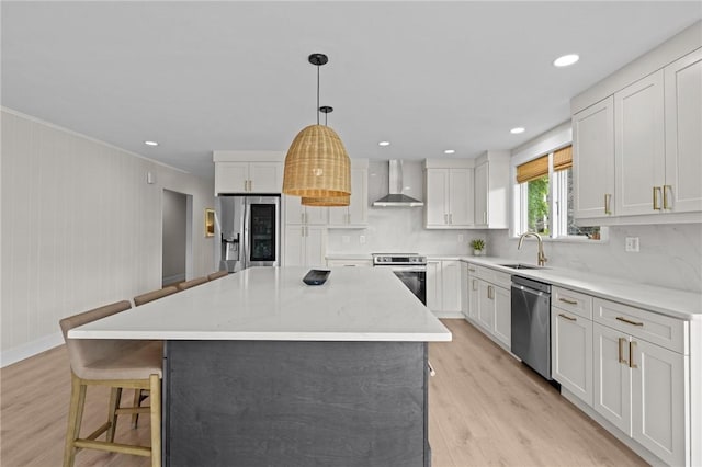 96 Roger Williams Dr, North Kingstown, RI 02852 - kitchen featuring appliances with stainless steel finishes, wall chimney range hood, a sink, light wood finished floors, and a breakfast bar