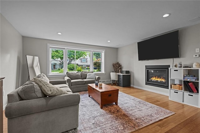 96 Roger Williams Dr, North Kingstown, RI 02852 - living room with wood finished floors, a glass covered fireplace, a baseboard heating unit, recessed lighting, and baseboards