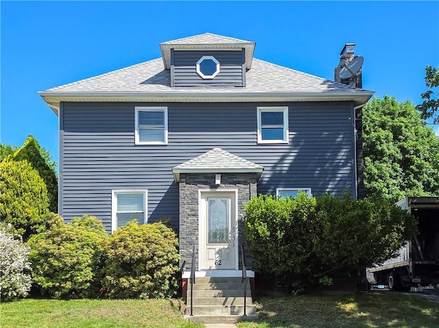 american foursquare style home featuring entry steps, a chimney, and roof with shingles
