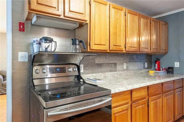 kitchen featuring stainless steel range with electric stovetop, decorative backsplash, and light stone countertops