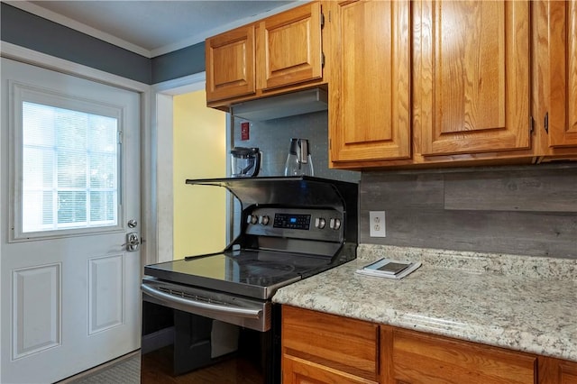 kitchen with stainless steel range with electric stovetop, decorative backsplash, brown cabinetry, and light stone counters