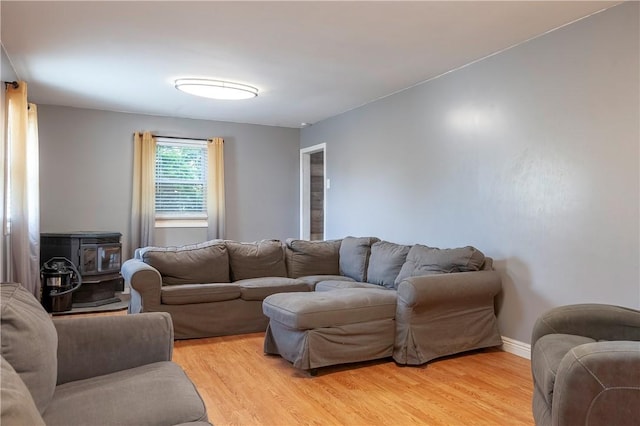 living room with a wood stove, light wood-style flooring, and baseboards