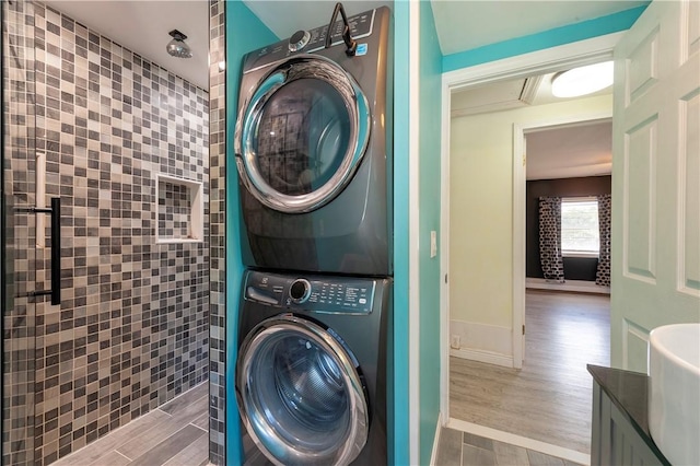 washroom with stacked washer and clothes dryer and wood finished floors