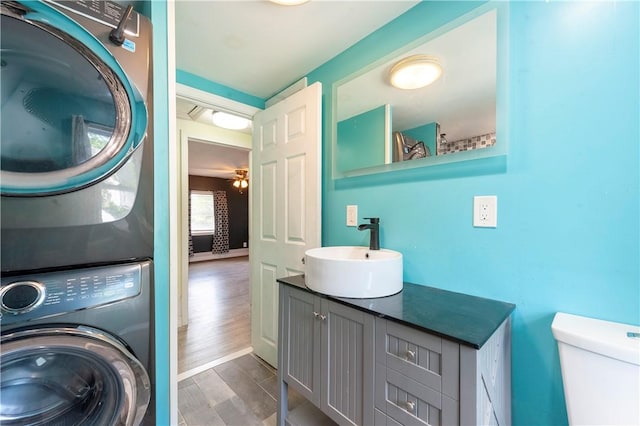 washroom featuring stacked washer / dryer, dark wood-type flooring, and a ceiling fan