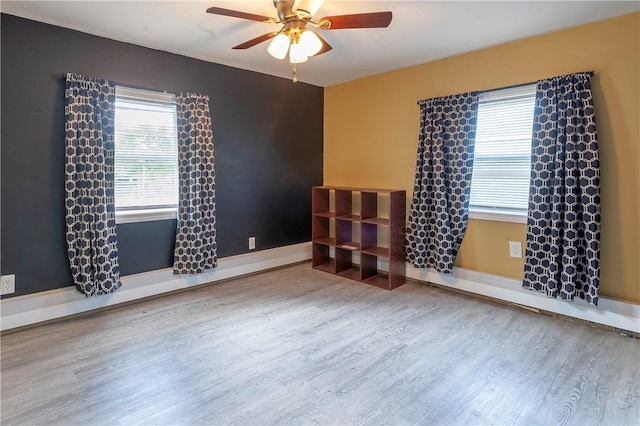 unfurnished room featuring wood finished floors, ceiling fan, and baseboards