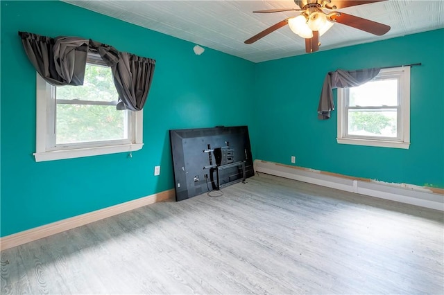 unfurnished living room featuring wood finished floors, plenty of natural light, baseboards, and ceiling fan