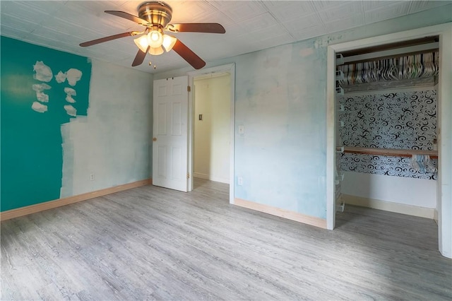 unfurnished bedroom with wood finished floors, baseboards, ceiling fan, and a closet