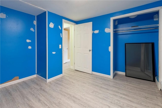 unfurnished bedroom with a closet, wood finished floors, and baseboards