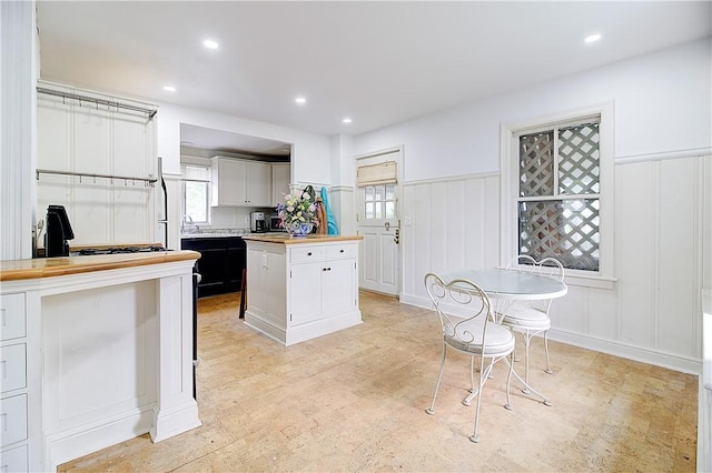 222 Second St, East Providence, RI 02865 - kitchen featuring a decorative wall, butcher block counters, white cabinets, wainscoting, and a kitchen island