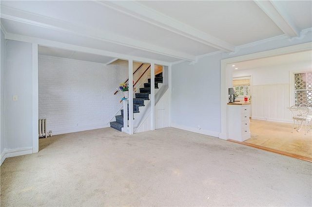 222 Second St, East Providence, RI 02865 - unfurnished living room with radiator heating unit, beam ceiling, stairs, light colored carpet, and brick wall