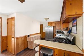 33 Merle St, Warwick, RI 02889 - kitchen featuring appliances with stainless steel finishes, dark wood-style flooring, brown cabinets, light countertops, and a wainscoted wall