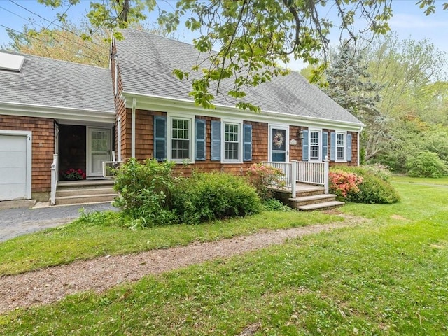 new england style home with a shingled roof, a front lawn, and an attached garage