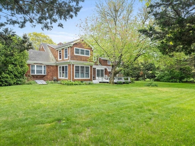 rear view of house with a wooden deck and a lawn