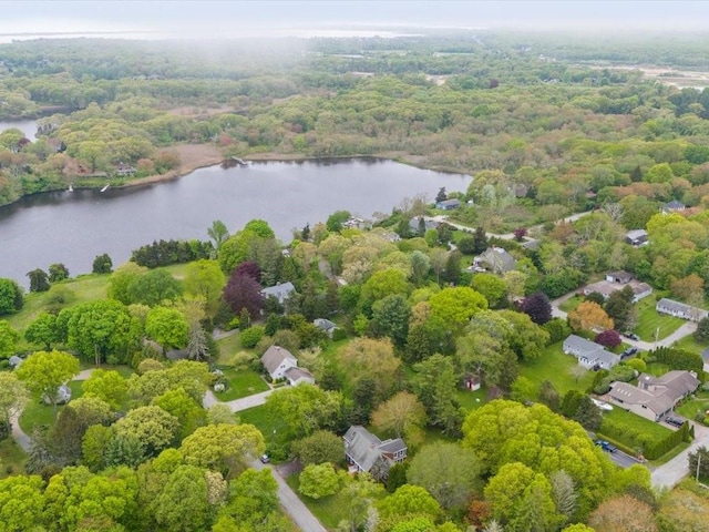 drone / aerial view of a nearby body of water and a heavily wooded area