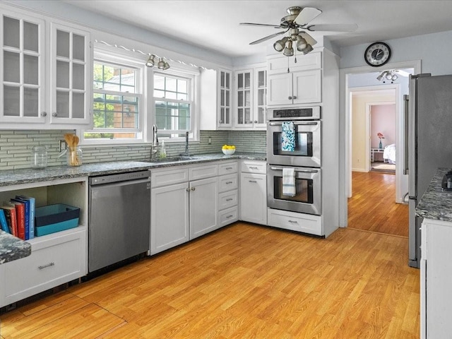 kitchen featuring stainless steel appliances, white cabinets, decorative backsplash, and a ceiling fan