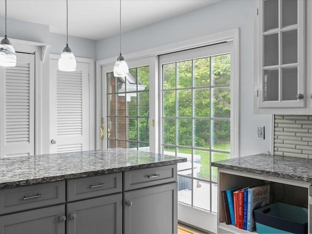 kitchen with gray cabinets, light stone counters, and hanging light fixtures