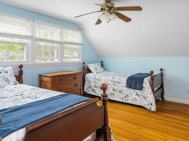 bedroom featuring wood finished floors, lofted ceiling, ceiling fan, and baseboards