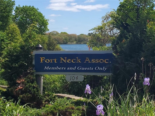 community / neighborhood sign featuring a wooded view and a water view