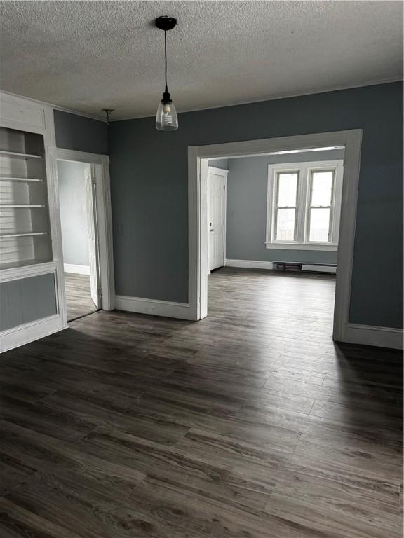 342 Paradis Ave, Woonsocket, RI 02895 - unfurnished dining area featuring a textured ceiling, a baseboard radiator, dark wood-type flooring, built in features, and baseboards