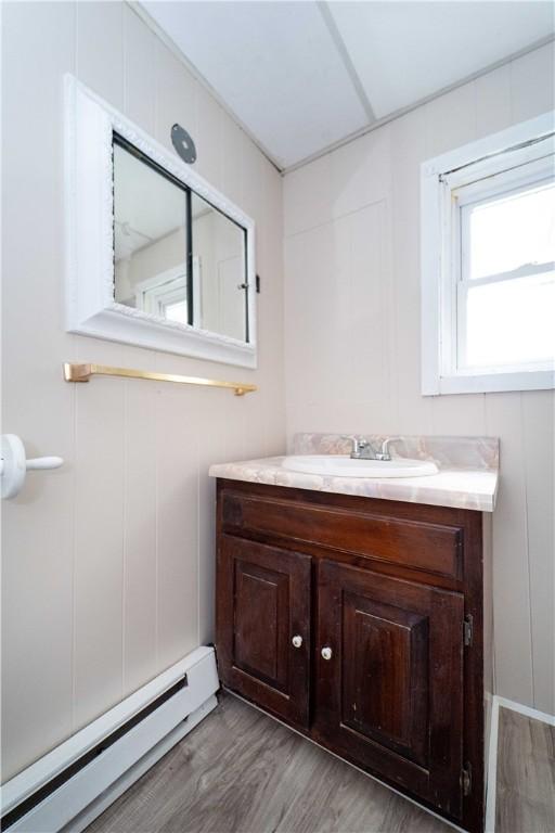 46 E Andrew Comstock Rd, Warwick, RI 02886 - bathroom featuring baseboard heating, vanity, and wood finished floors