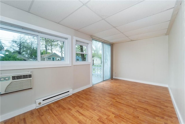 46 E Andrew Comstock Rd, Warwick, RI 02886 - empty room with baseboard heating, a paneled ceiling, light wood-style flooring, a wall mounted air conditioner, and baseboards