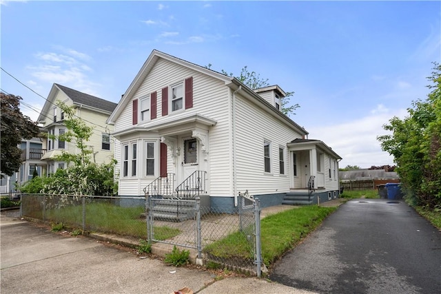 traditional-style home with a fenced front yard, a gate, and asphalt driveway