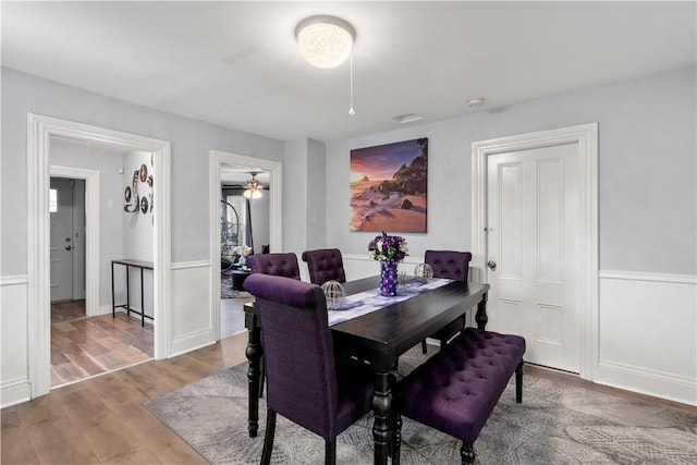 dining space featuring wood finished floors and wainscoting