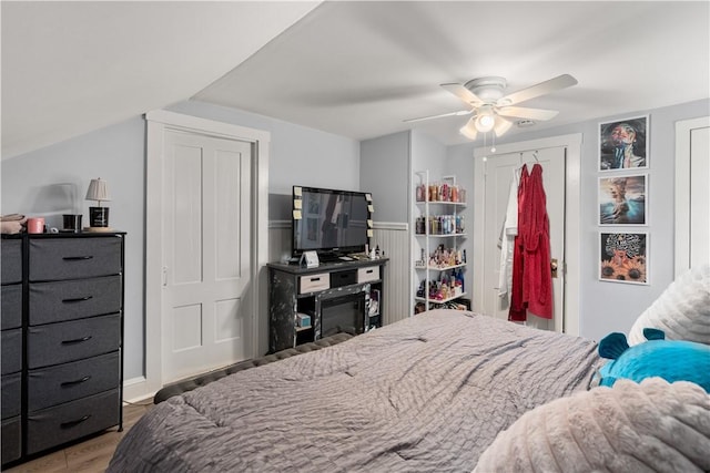 bedroom featuring a closet, wood finished floors, ceiling fan, and a wainscoted wall