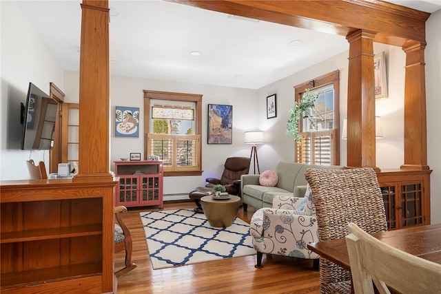 living room with ornate columns, a baseboard heating unit, and wood finished floors