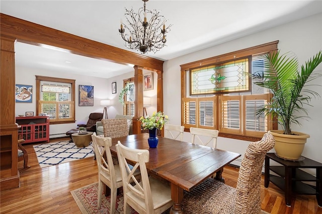 dining room with ornate columns, light wood-style flooring, and a chandelier
