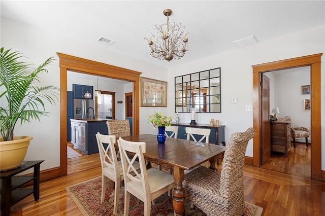 dining area featuring a chandelier, light wood-type flooring, baseboards, and a baseboard heating unit