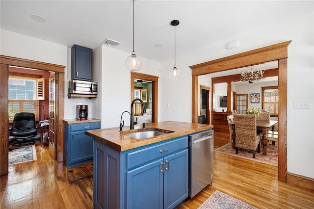 kitchen featuring stainless steel appliances, blue cabinetry, a sink, wooden counters, and light wood-style flooring