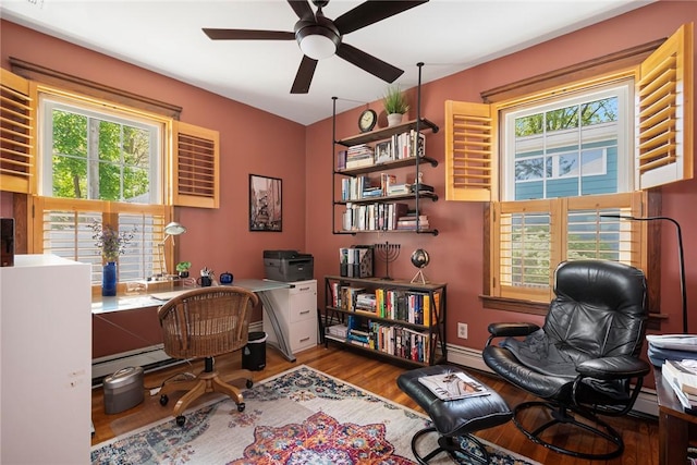 office area featuring wood finished floors, a ceiling fan, and a baseboard heating unit