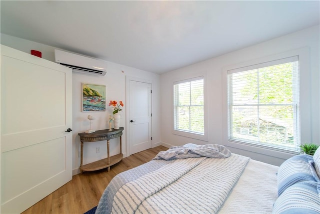 32 Exchange St Unit 101, East Greenwich, RI 02818 - bedroom with a wall mounted air conditioner, light wood-style flooring, and baseboards