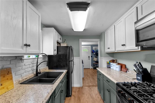40 Glen St, East Providence, RI 02915 - kitchen featuring stainless steel microwave, gas range, a sink, white cabinets, and a wainscoted wall