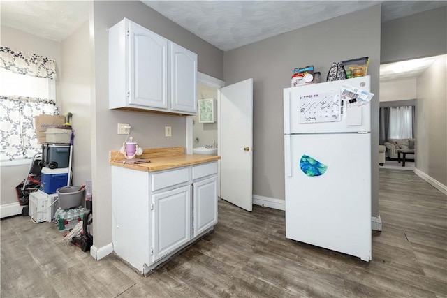 115 Division St, Pawtucket, RI 02860 - kitchen featuring freestanding refrigerator, wood finished floors, white cabinetry, and baseboards