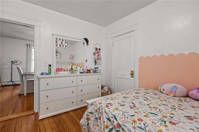 bedroom with wood finished floors and a baseboard heating unit