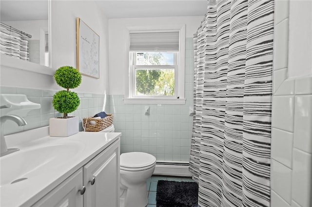 bathroom with tile patterned flooring, tile walls, a baseboard heating unit, toilet, and vanity
